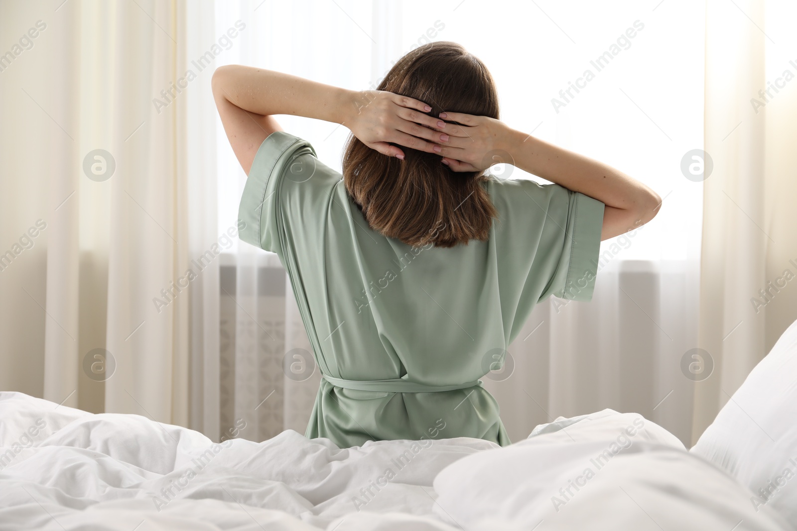 Woman stretching in bed at home, back view Photo of Woman stretching in bed at home, back view