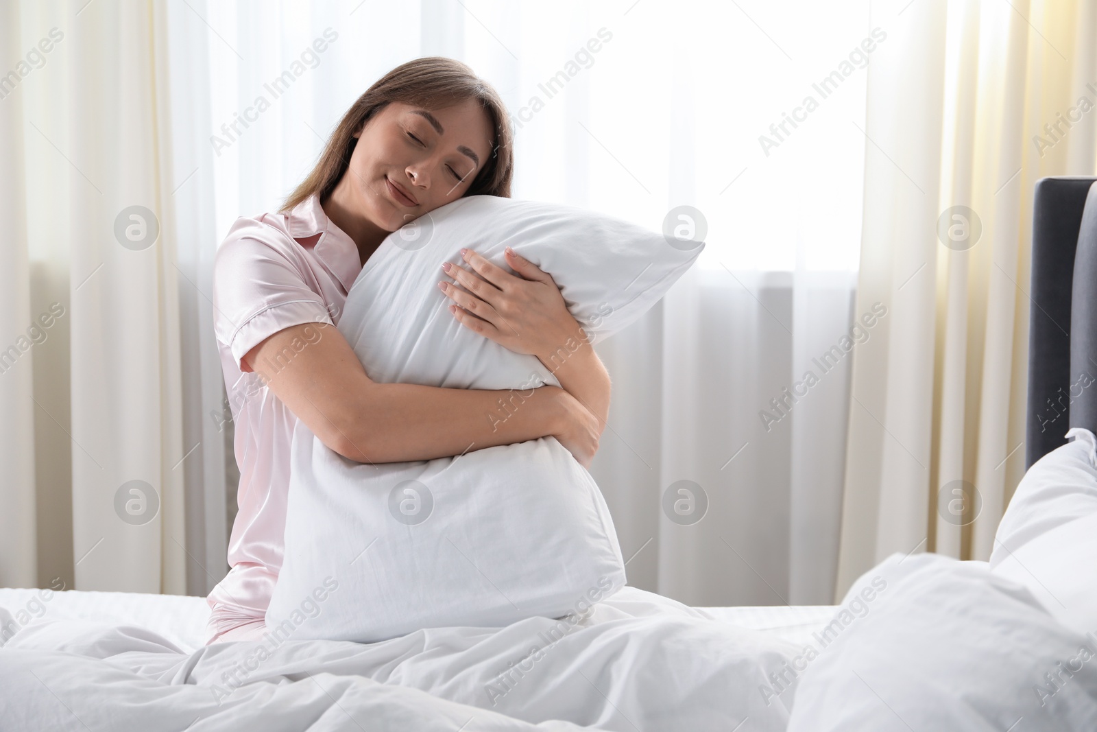 Beautiful woman with pillow in bed at home Photo of Beautiful woman with pillow in bed at home