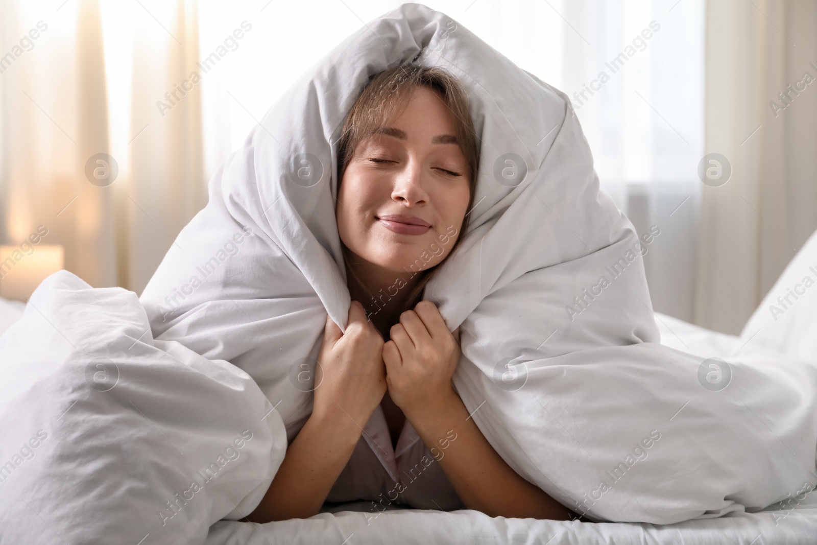 Beautiful woman wrapped in blanket on bed at home Photo of Beautiful woman wrapped in blanket on bed at home