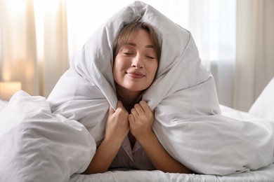 Photo of Beautiful woman wrapped in blanket on bed at home