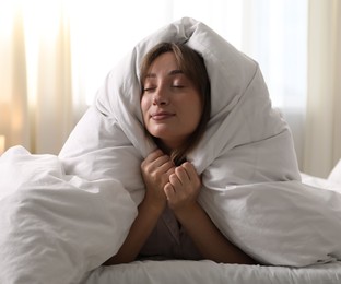 Photo of Beautiful woman wrapped in blanket on bed at home