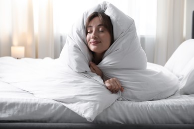 Photo of Beautiful woman wrapped in blanket on bed at home