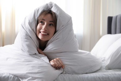 Photo of Beautiful woman wrapped in blanket on bed at home