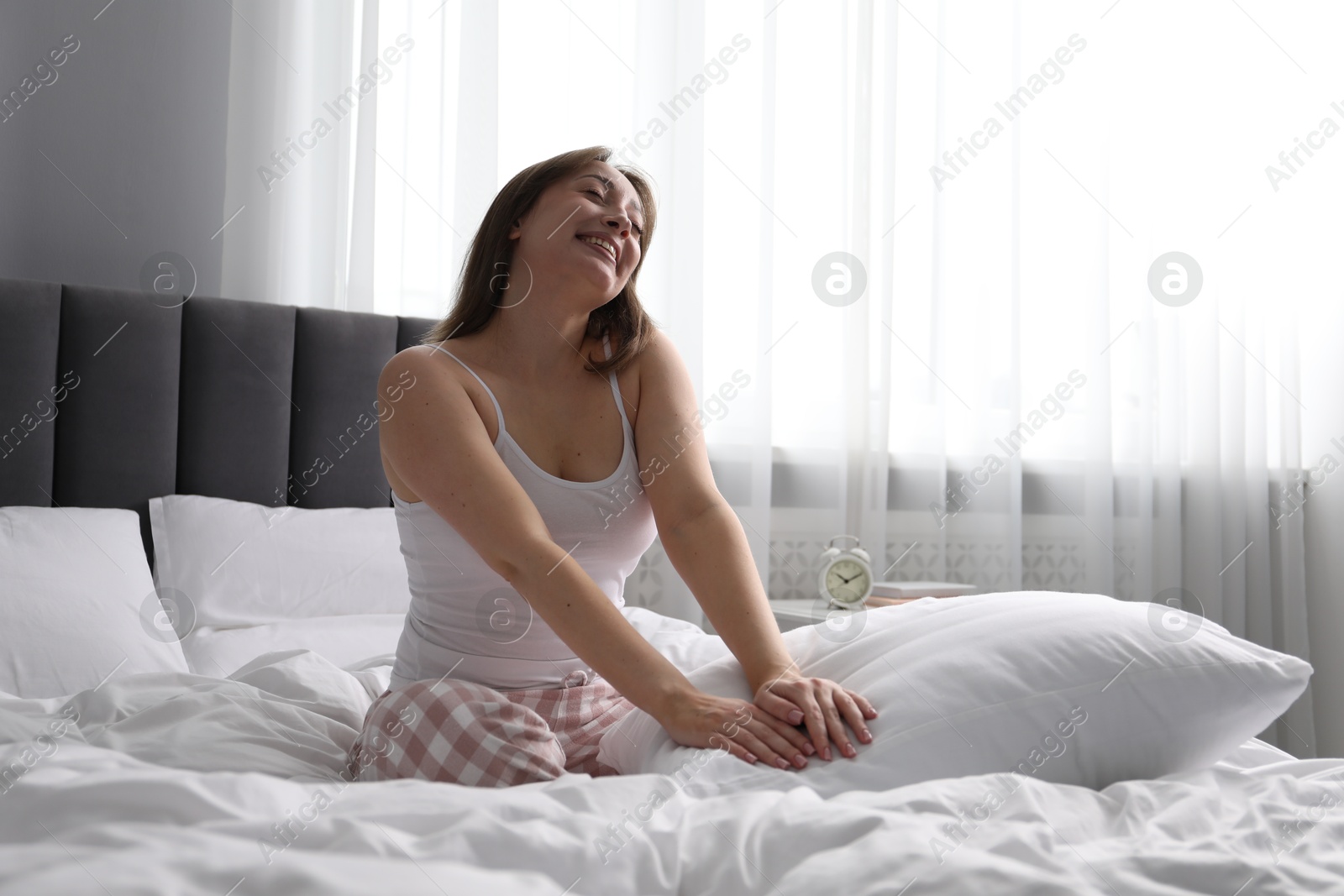 Beautiful woman with pillow on bed at home Photo of Beautiful woman with pillow on bed at home