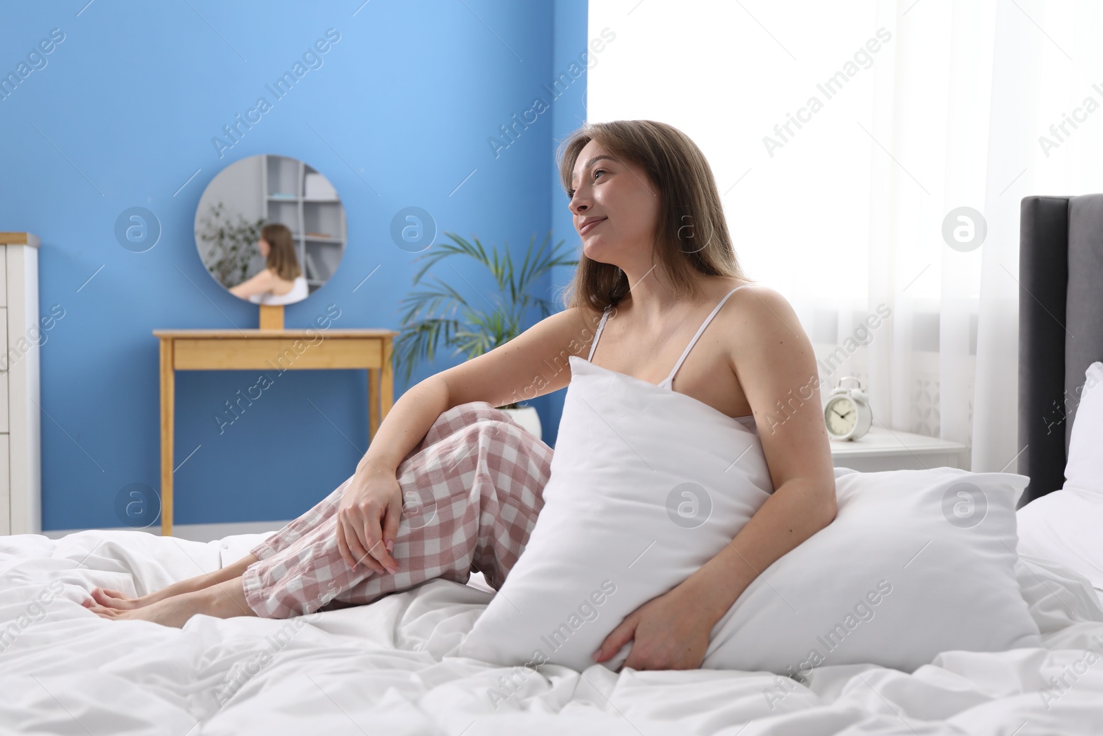 Beautiful woman with pillow on bed at home Photo of Beautiful woman with pillow on bed at home
