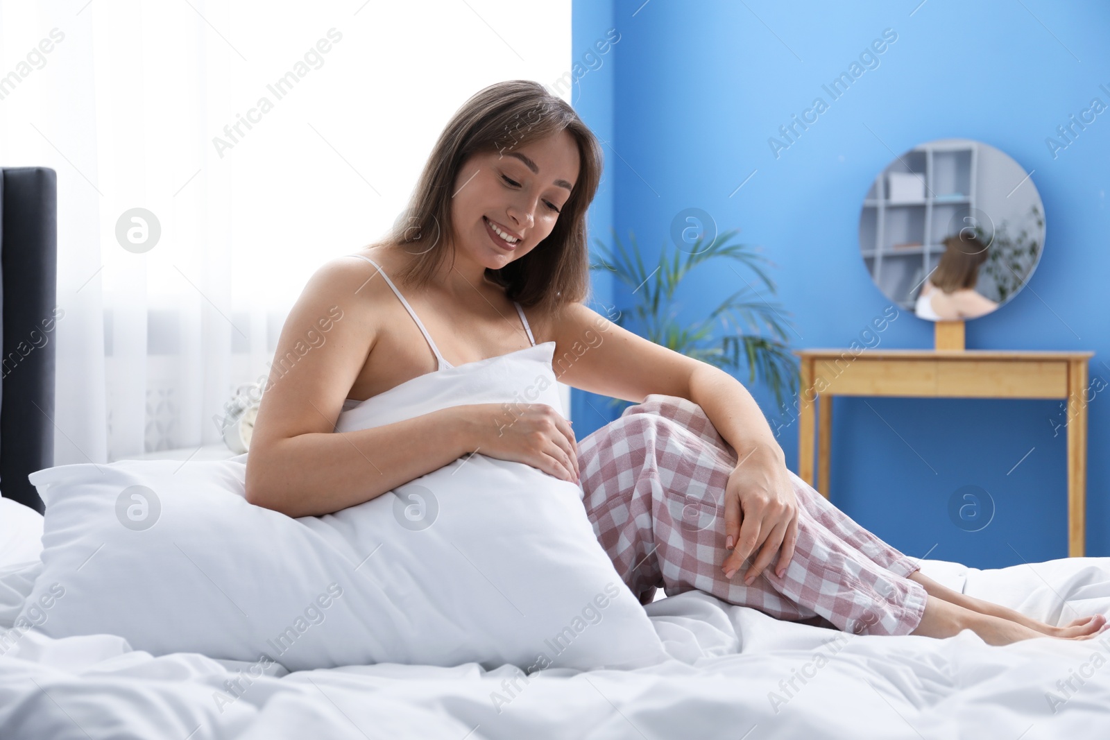 Beautiful woman with pillow on bed at home Photo of Beautiful woman with pillow on bed at home