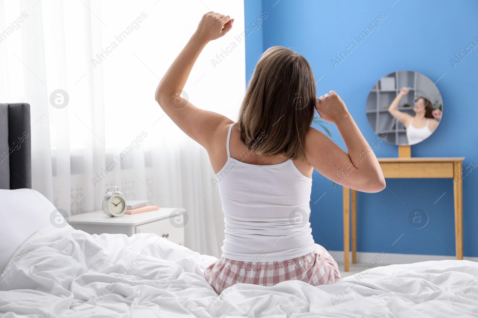 Woman stretching in bed at home, back view Photo of Woman stretching in bed at home, back view