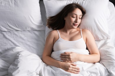 Photo of Beautiful woman sleeping in bed at home, top view