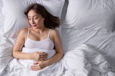 Photo of Beautiful woman sleeping in bed at home, top view
