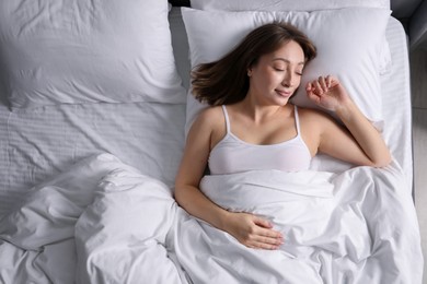 Photo of Beautiful woman sleeping in bed at home, top view