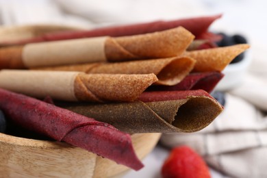 Photo of Tasty fruit leather rolls and berries on white table, closeup