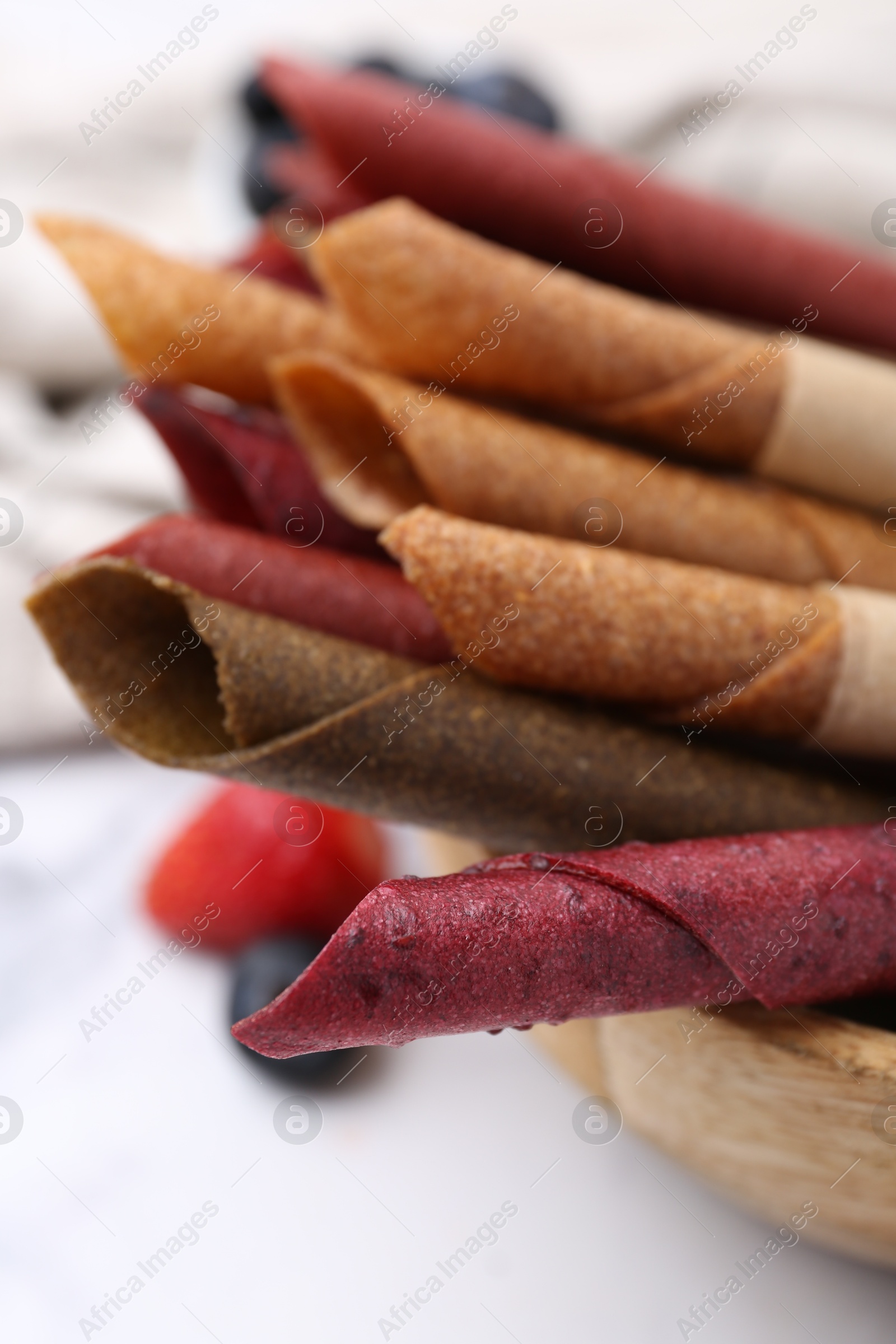 Tasty fruit leather rolls and berries on white table, closeup Photo of Tasty fruit leather rolls and berries on white table, closeup