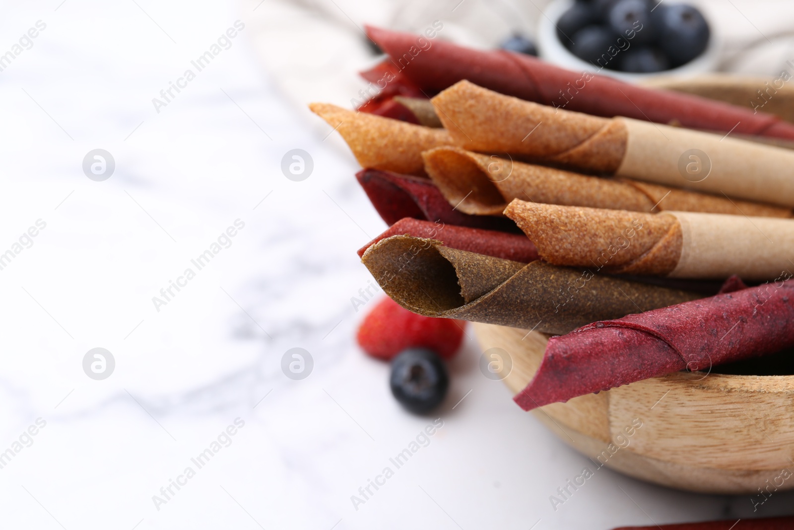 Tasty fruit leather rolls and berries on white marble table, closeup. Space for text Photo of Tasty fruit leather rolls and berries on white marble table, closeup. Space for text