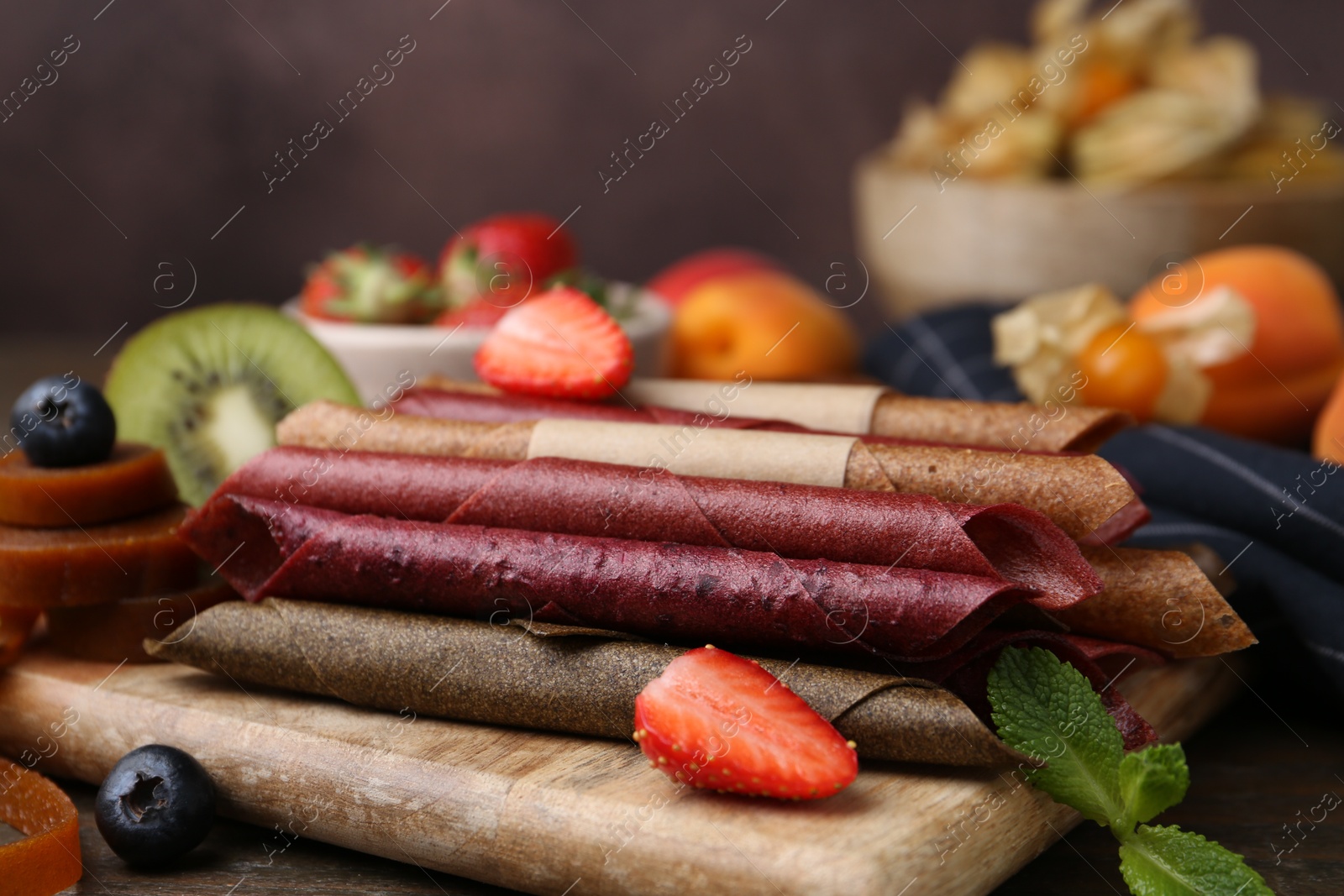 Tasty candied leather rolls, fruits and berries on wooden table, closeup Photo of Tasty candied leather rolls, fruits and berries on wooden table, closeup