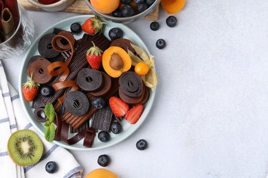 Photo of Tasty candied leather rolls, fruits and berries on white table, flat lay. Space for text