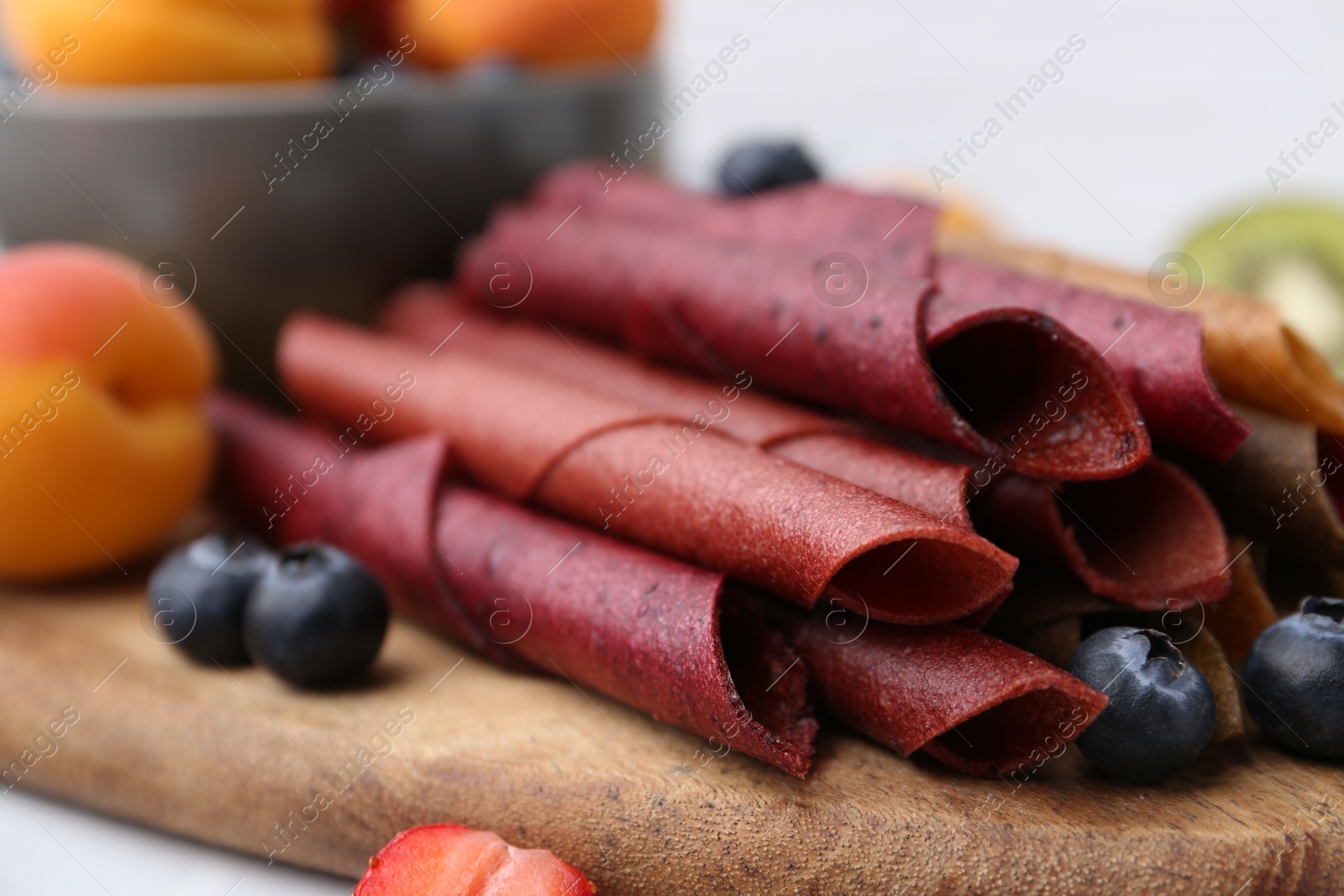 Tasty candied leather rolls, fruits and berries on white table, closeup Photo of Tasty candied leather rolls, fruits and berries on white table, closeup