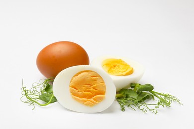 Photo of Boiled eggs and microgreens on white background