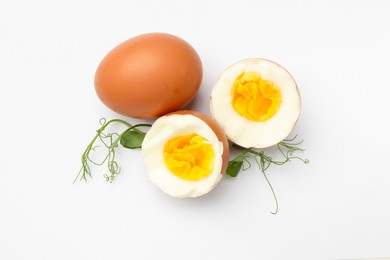 Photo of Hard boiled eggs and microgreens on white background, top view
