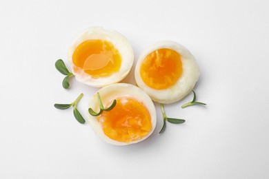 Photo of Soft boiled eggs with microgreens on white background, top view