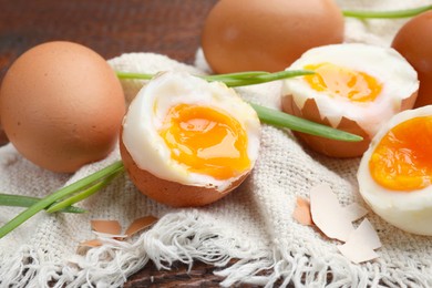 Photo of Soft boiled eggs with green onions on wooden table, closeup
