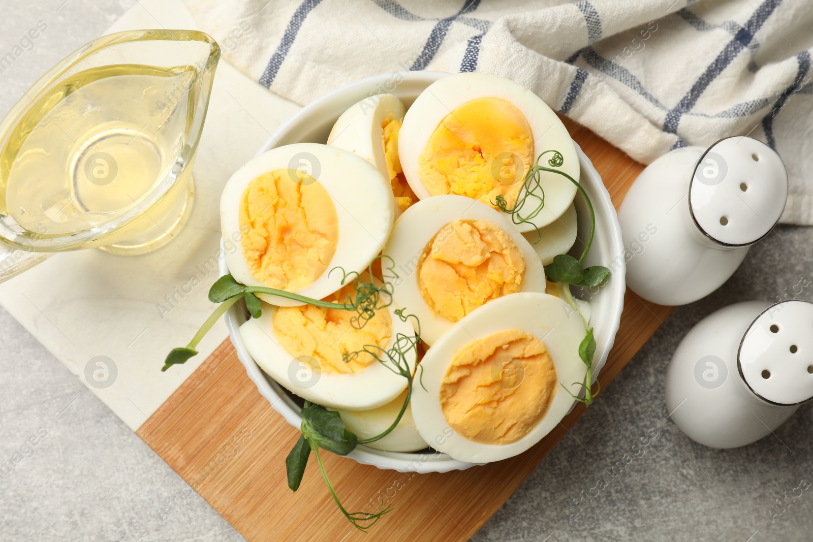 Hard boiled eggs with microgreens on grey table, flat lay Photo of Hard boiled eggs with microgreens on grey table, flat lay