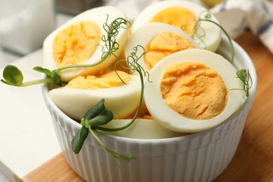 Photo of Hard boiled eggs with microgreens on grey table, closeup