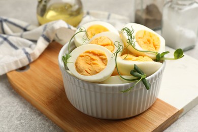 Photo of Hard boiled eggs with microgreens on grey table, closeup