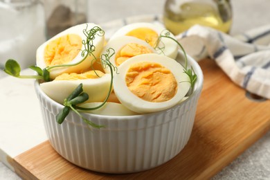 Photo of Hard boiled eggs with microgreens on grey table, closeup