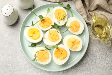 Photo of Hard boiled eggs with microgreens on grey table, flat lay