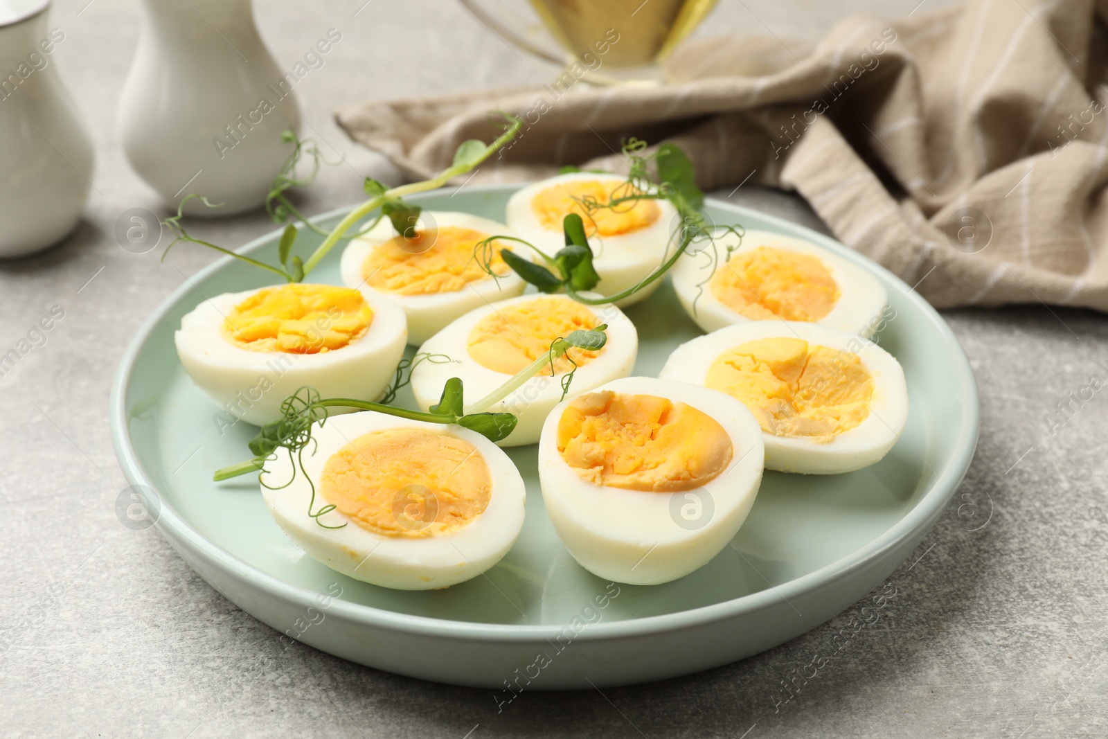 Hard boiled eggs with microgreens on grey table, closeup Photo of Hard boiled eggs with microgreens on grey table, closeup