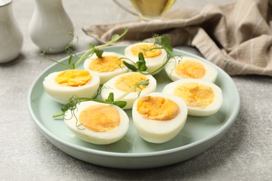 Photo of Hard boiled eggs with microgreens on grey table, closeup