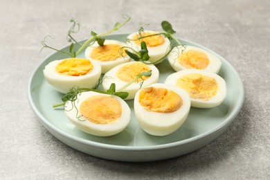 Photo of Hard boiled eggs with microgreens on grey table, closeup