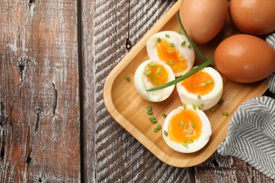 Photo of Soft boiled eggs with green onions on wooden table, top view. Space for text