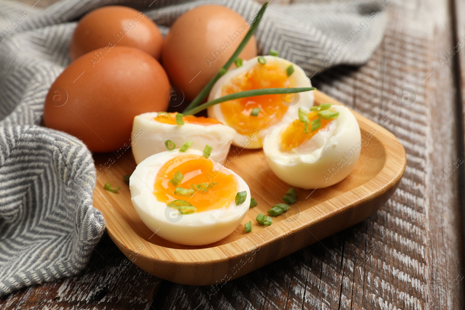Soft boiled eggs with green onions on wooden table, closeup Photo of Soft boiled eggs with green onions on wooden table, closeup