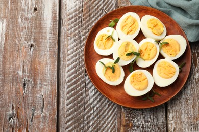 Photo of Hard boiled eggs with microgreens on wooden table, top view. Space for text