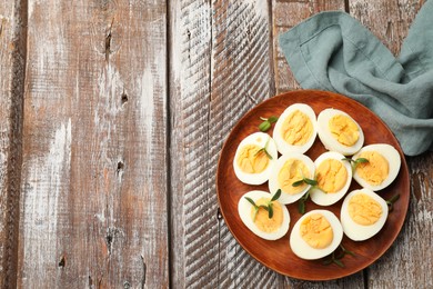 Photo of Hard boiled eggs with microgreens on wooden table, top view. Space for text