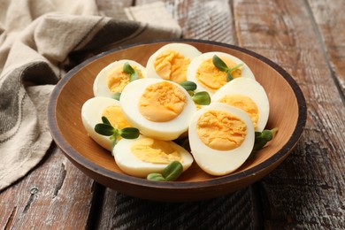 Photo of Hard boiled eggs with microgreens on wooden table, closeup