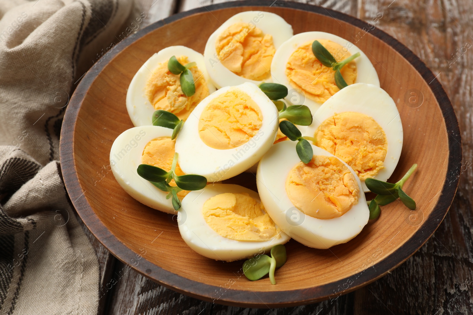 Hard boiled eggs with microgreens on wooden table, closeup Photo of Hard boiled eggs with microgreens on wooden table, closeup