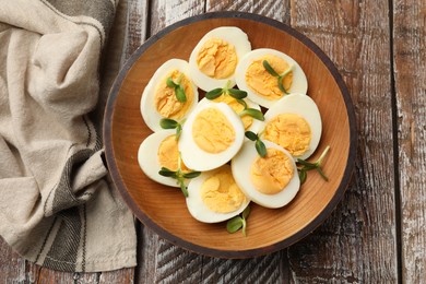 Photo of Hard boiled eggs with microgreens on wooden table, top view