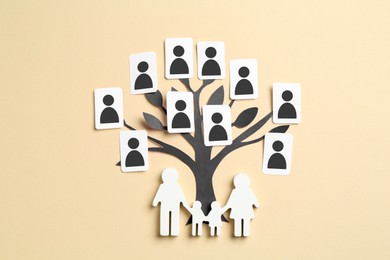 Image of Family tree. Cards with human icons attached to paper tree on beige background, top view