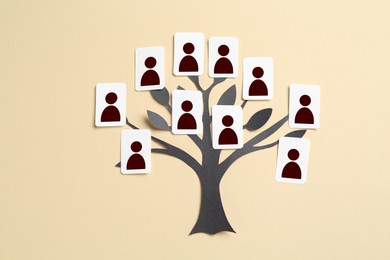 Image of Family tree. Cards with human icons attached to paper tree on beige background, top view