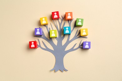 Image of Family tree. Colorful cubes with human icons and paper tree on beige background, top view