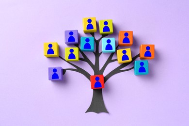 Image of Family tree. Colorful cubes with human icons and paper tree on violet background, top view