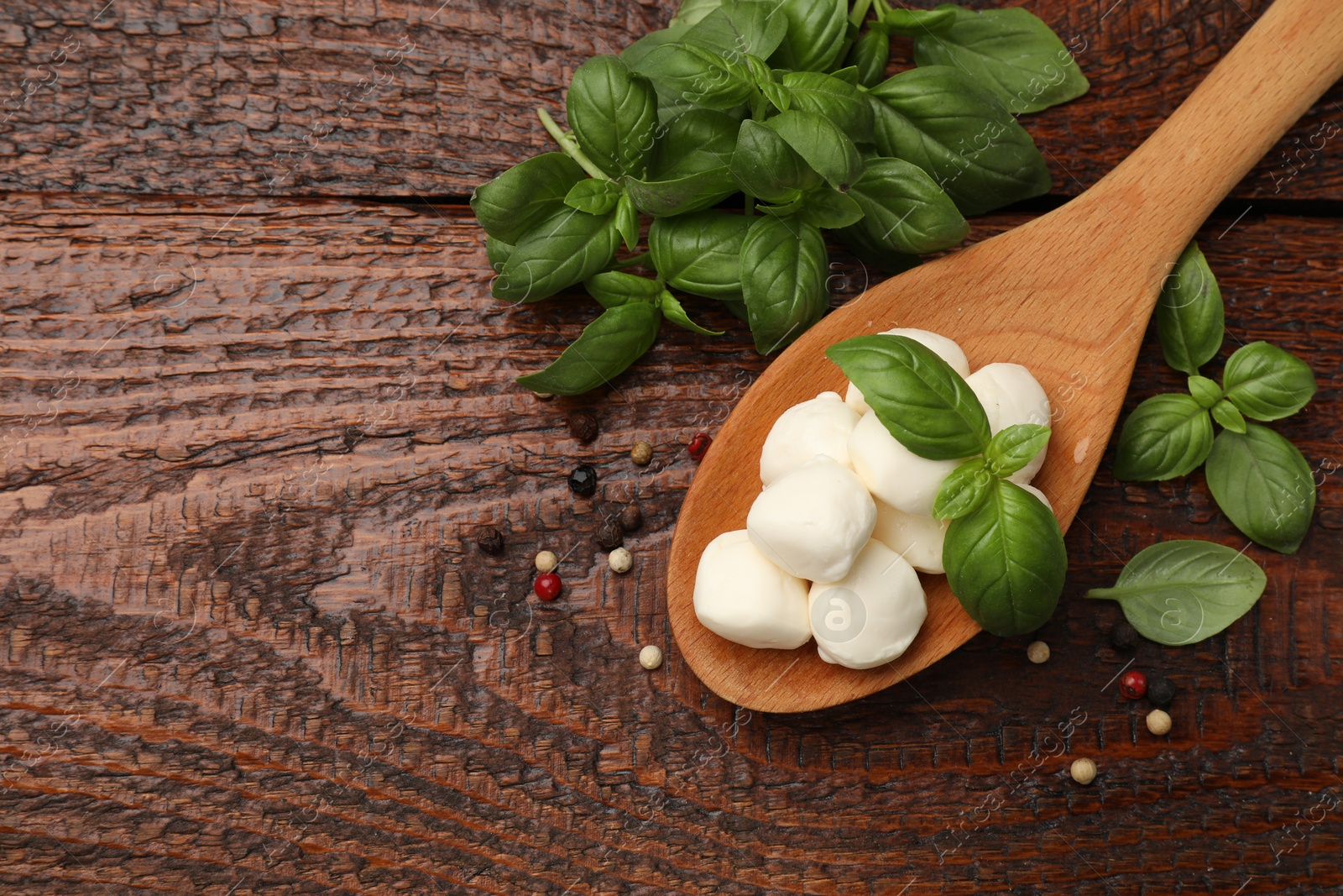 Tasty mozzarella cheese balls in spoon, peppercorns and basil on wooden table, flat lay. Space for text Photo of Tasty mozzarella cheese balls in spoon, peppercorns and basil on wooden table, flat lay. Space for text