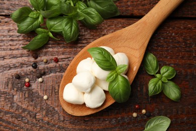 Photo of Tasty mozzarella cheese balls in spoon, peppercorns and basil on wooden table, flat lay