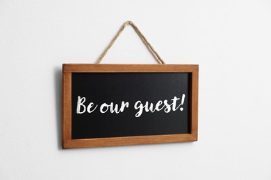 Image of Small blackboard with phrase Be Our Guest hanging on white wall
