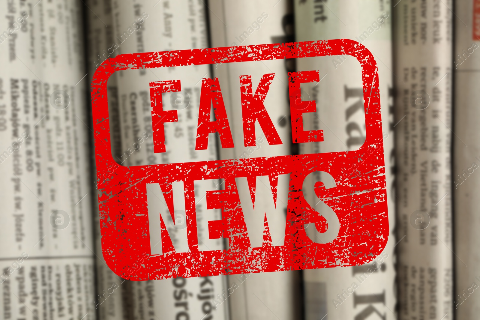 Red Fake News stamp and newspapers in different languages as background, closeup Image of Red Fake News stamp and newspapers in different languages as background, closeup