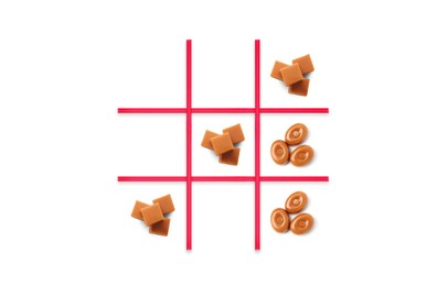 Image of Tic-tac-toe game made of hard toffee and caramel candies on white background, top view