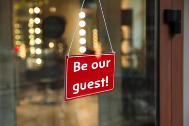 Image of Be Our Guest sign hanging on glass door outdoors