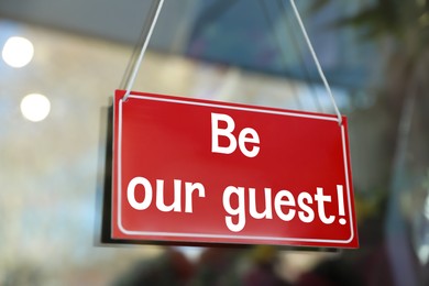 Image of Be Our Guest sign hanging on glass outdoors